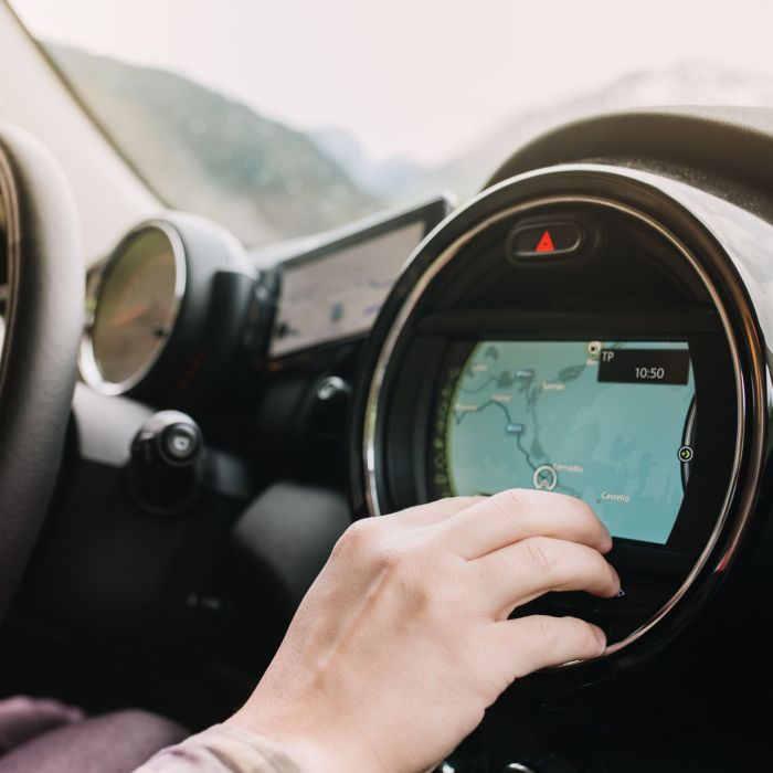 Man sitting in the car with black interior and looking at the new route laid by the navigator. Driver waiting for the itinerary to be made up before journey..