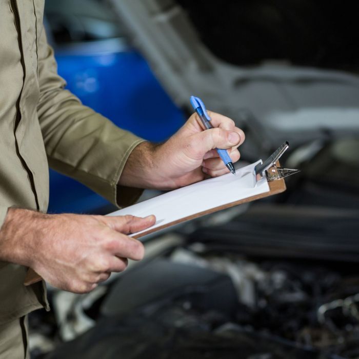 Mid-section of mechanic preparing a check list